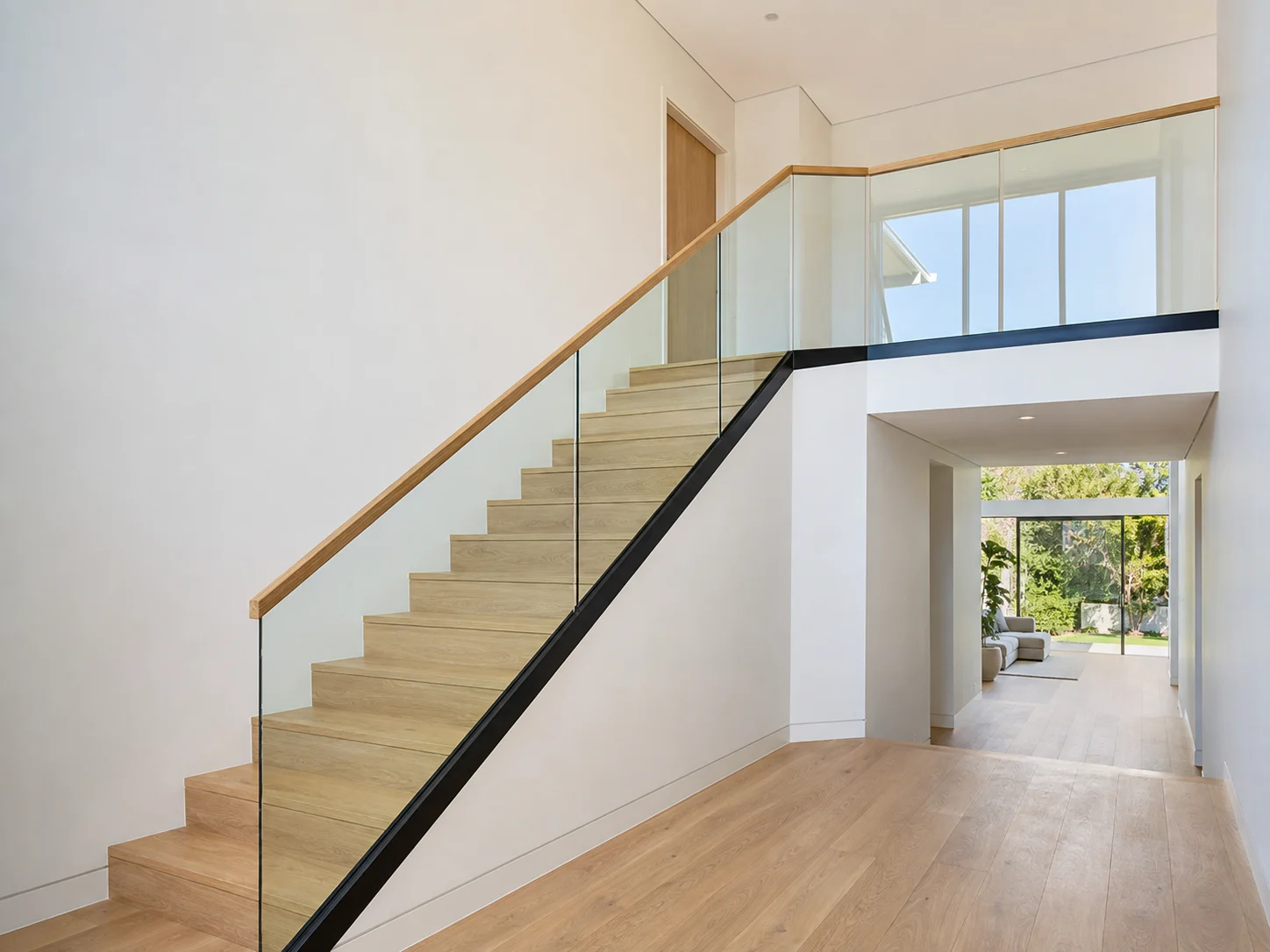 Interior glass stair and landing balustrade with a continuous timber handrail
